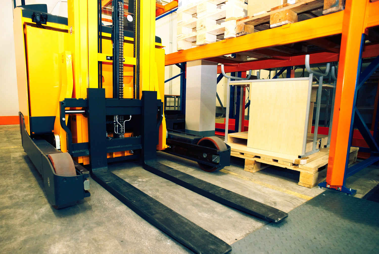 Electric forklift in warehouse positioned near loaded pallets