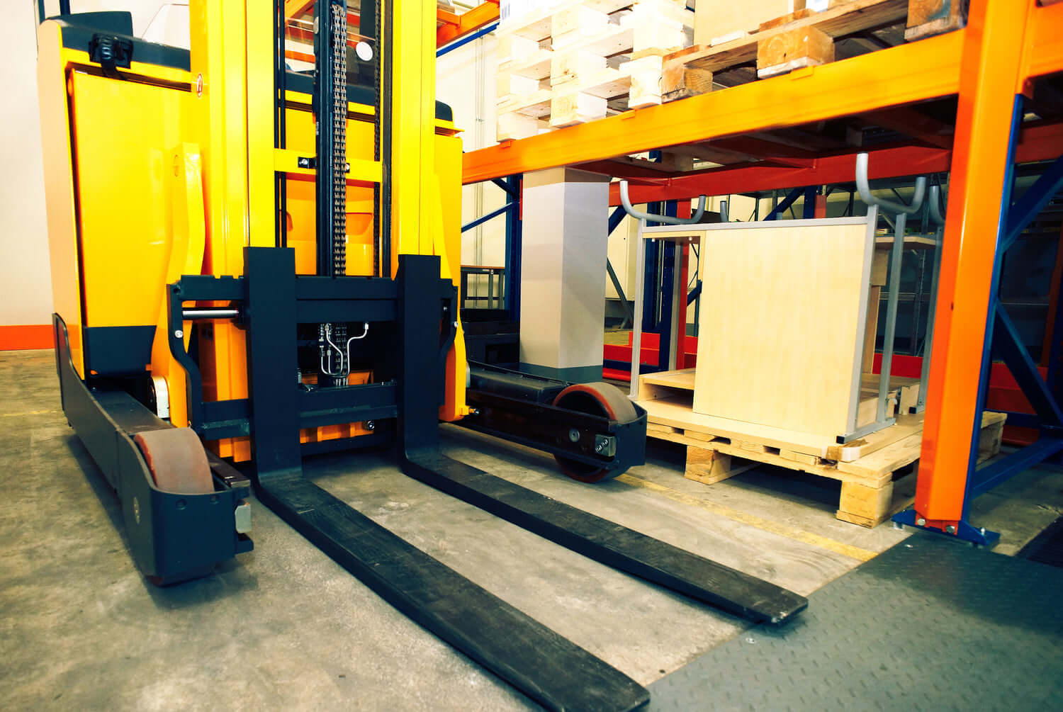 Electric forklift in warehouse positioned near loaded pallets