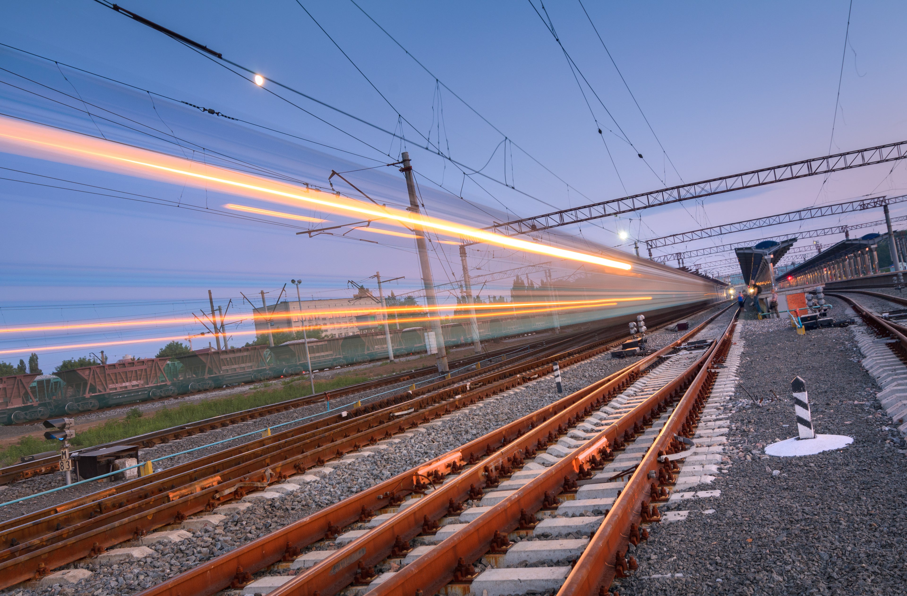 Blurred high-speed train passing through railway tracks at dusk