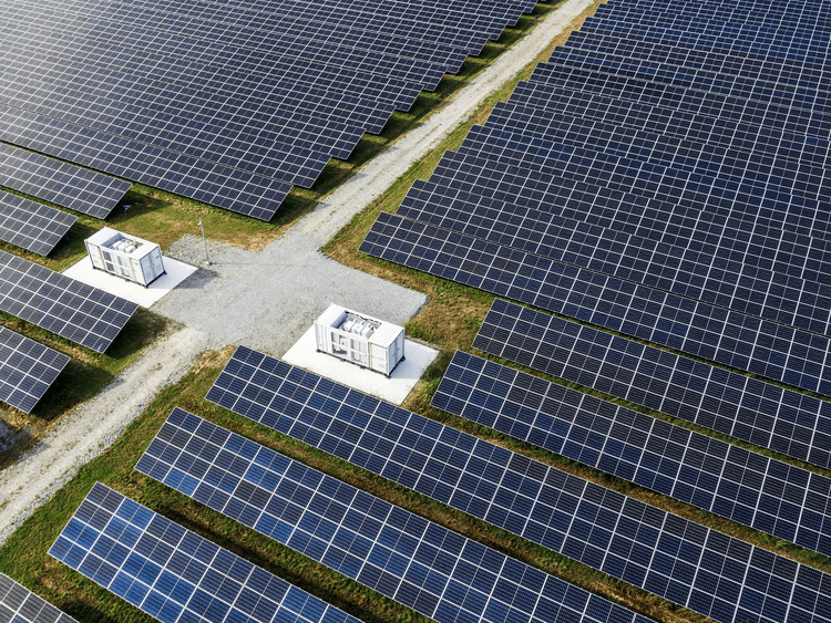 Aerial view of a solar farm with rows of photovoltaic panels and inverter stations