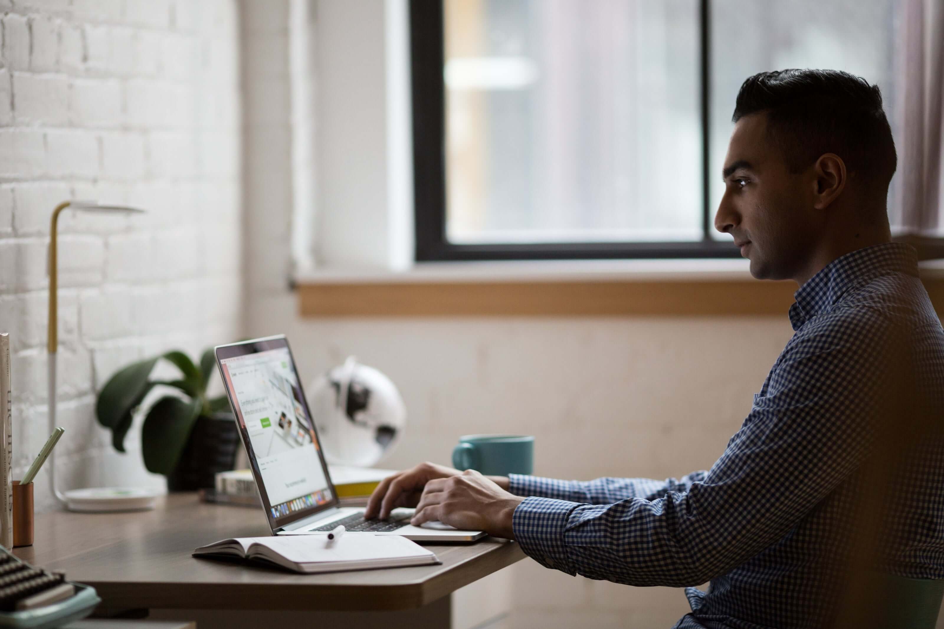 Man working on laptop at desk in modern office setting