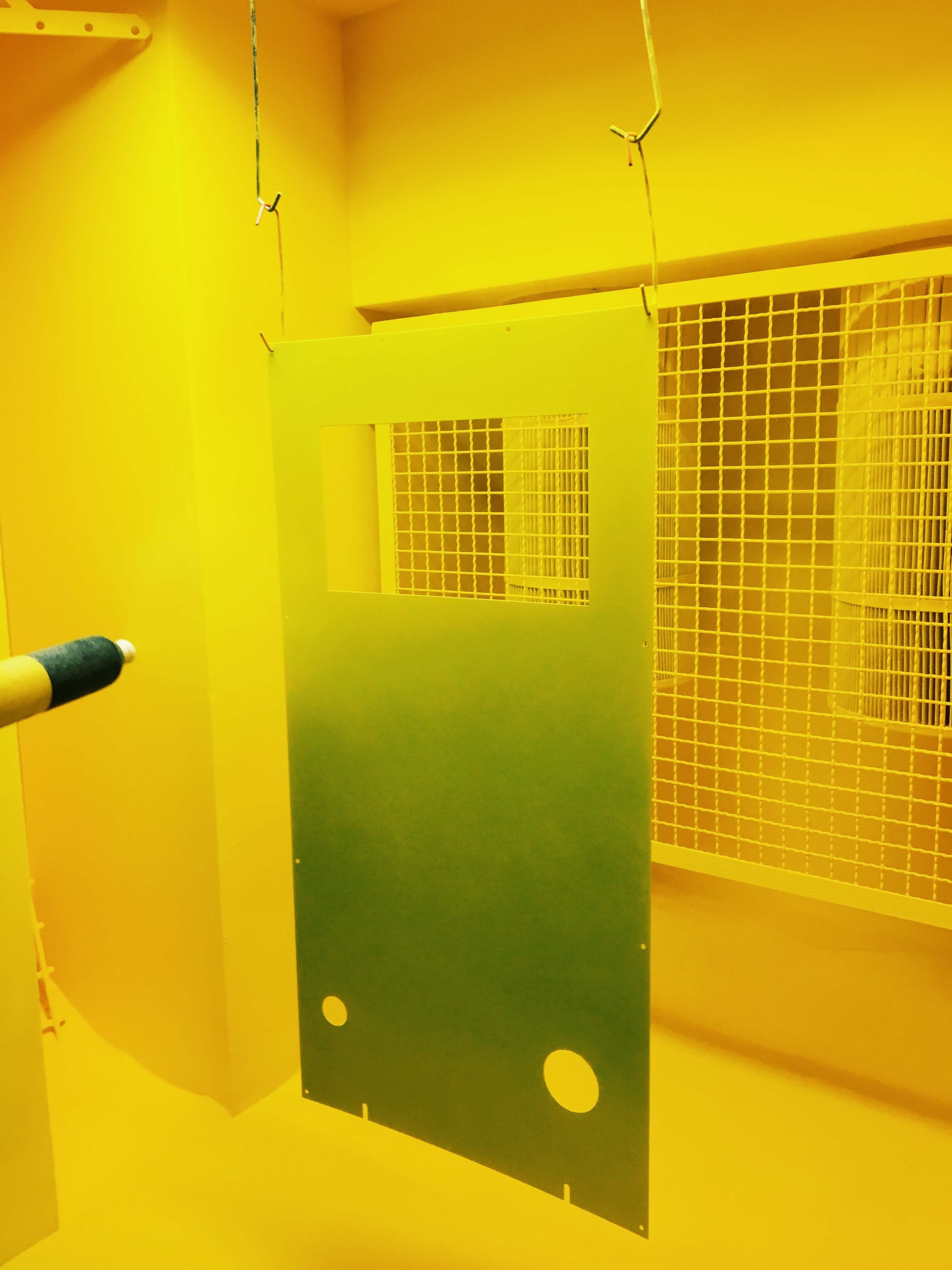 Metal panel being powder coated in a spray booth