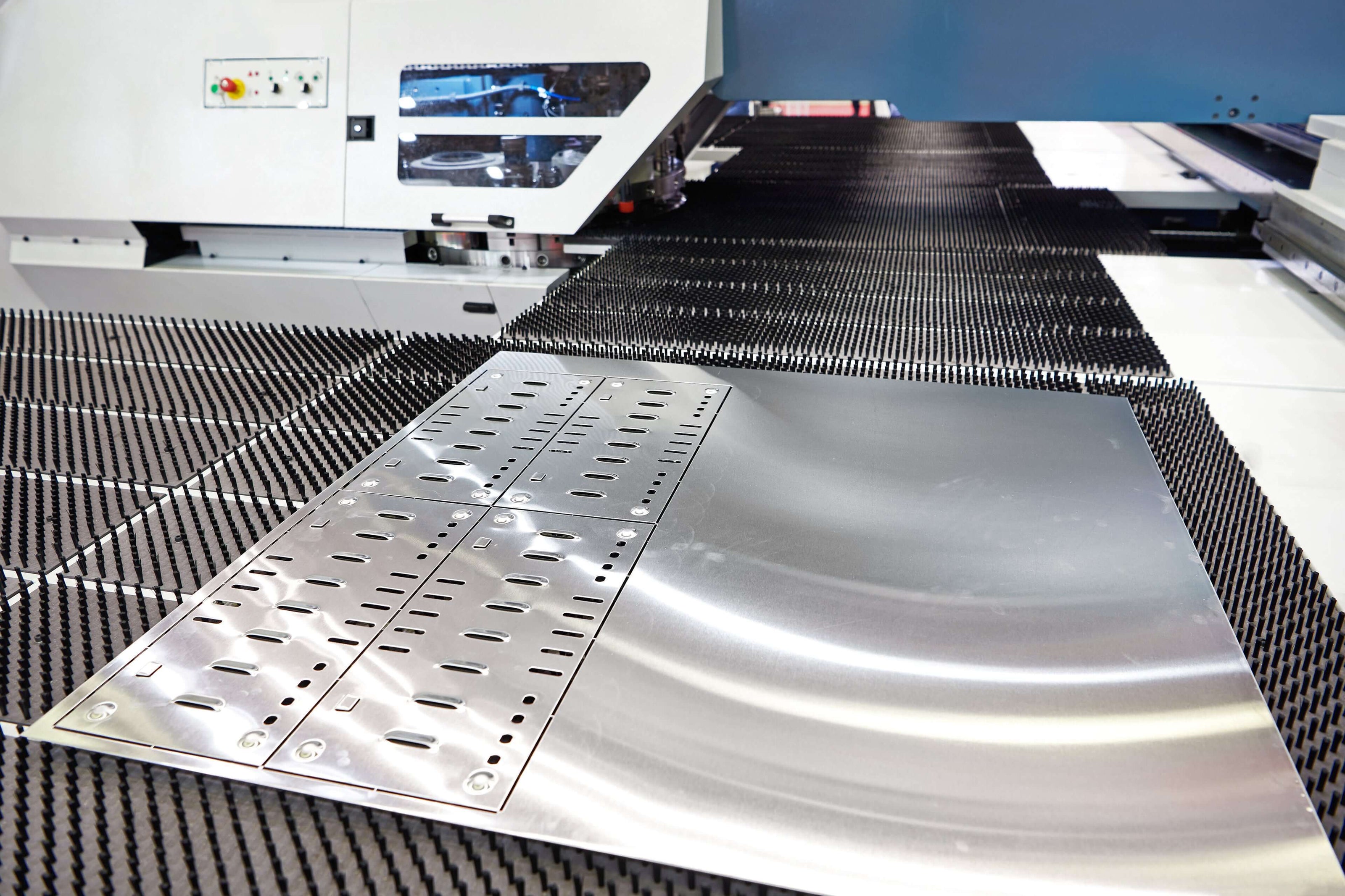 CNC machine punching holes into stainless steel sheet