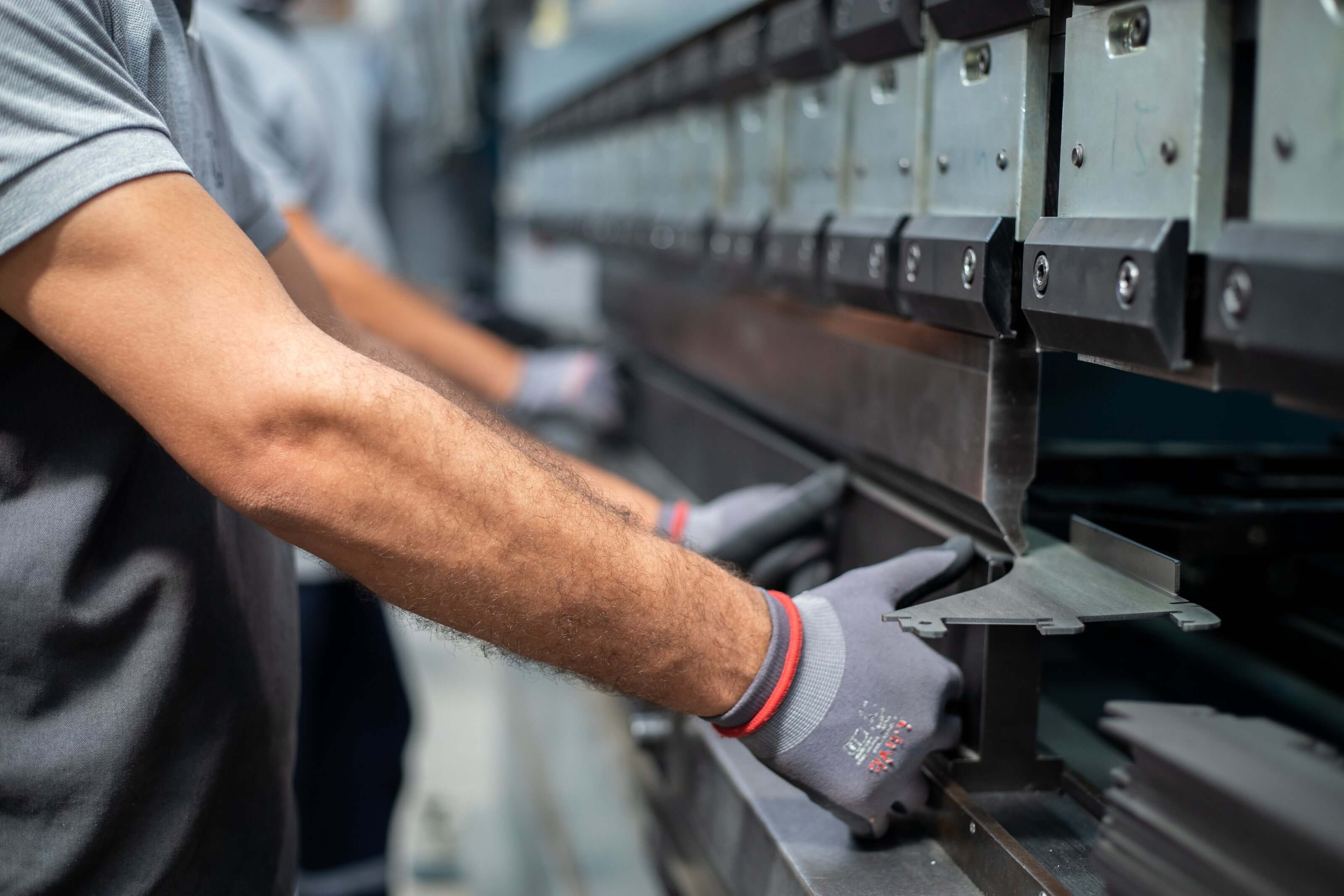 Worker operating a press brake machine to bend metal sheet